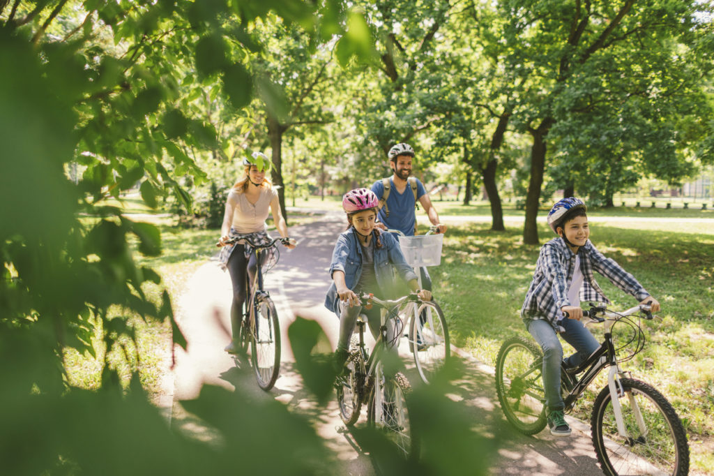 Family riding bikes on a wooded park path
